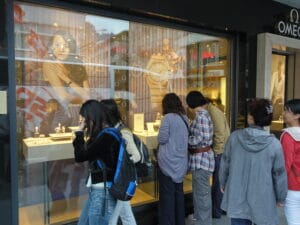 أشخاص يقفون أمام واجهة متجر ساعات سويسرية فاخرة من علامة أوميغا (Omega)