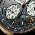 ساعة يد فاخرة ألمانية الصنع من A. Lange & Söhne، مصنوعة من الذهب Honeygold®️، تتميز بتصميمها المعقد ووظائفها المتعددة، بما في ذلك عرض التاريخ واليوم والشهر، بالإضافة إلى مراحل القمر.