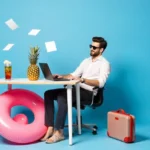 صورة رمزية تعكس نمط حياة العامل الحر، حيث يظهر رجل يجلس على مكتب بسيط أمام حاسوبه المحمول، محاط بعناصر تعبر عن الراحة والإبداع مثل طوق سباحة، أناناس، وحقيبة سفر، مما يشير إلى الحرية والمرونة التي يوفرها العمل الحر.