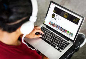 رجل يرتدي سماعات رأس ويستخدم جهاز لابتوب لمشاهدة قناة "أبو فلة" على يوتيوب، وهي واحدة من أكبر قنوات اليوتيوب العربية المتخصصة في المحتوى الترفيهي والألعاب، والتي تحظى بملايين المتابعين في العالم العربي. تعرف علي اكبر 10 قنوات اليوتيوب العربية.