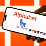 صورة لهاتف ذكي محمول باليد، تعرض شاشته شعارات ثلاث شركات كبرى: Alphabet، Novo Nordisk، وFortinet. تظهر الخلفية بألوان برتقالية لامعة مع نمط شبكي، مما يمنح المشهد طابعًا عصريًا يعكس قوة العلامات التجارية وتأثيرها في الأسواق العالمية.